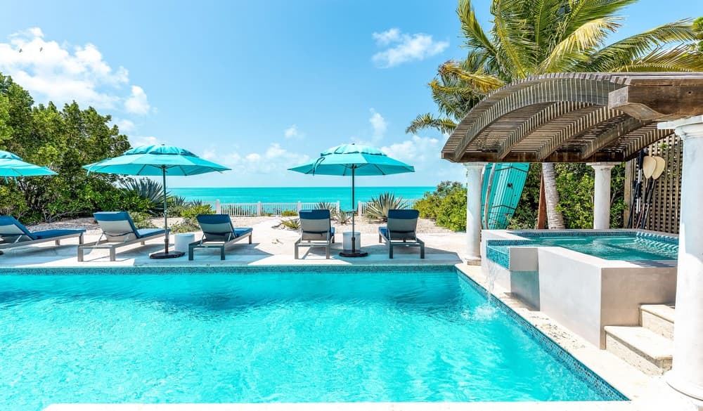Pool, hot tub, lounge chairs and umbrellas facing the ocean